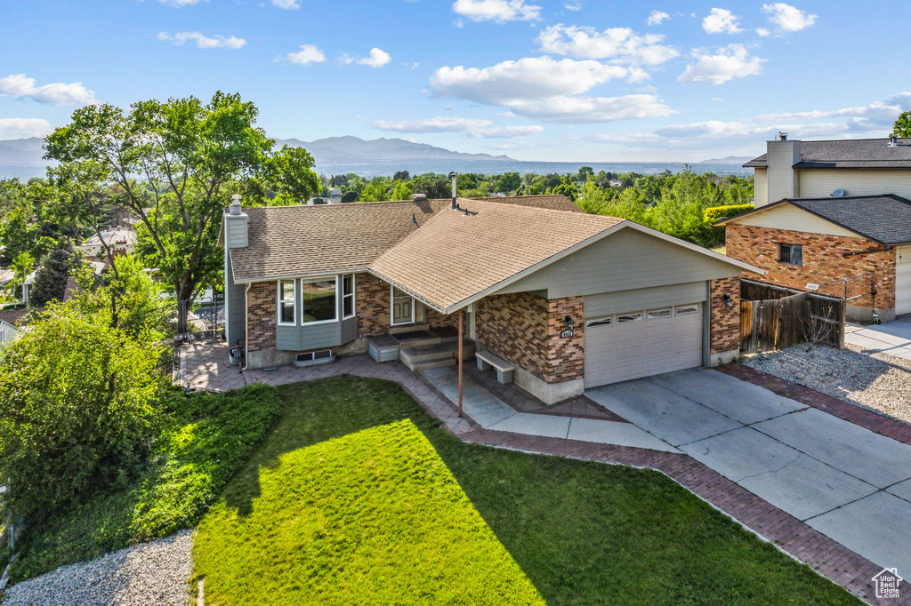 View of front of property with a mountain view, a garage, a chimney, driveway, and stone siding