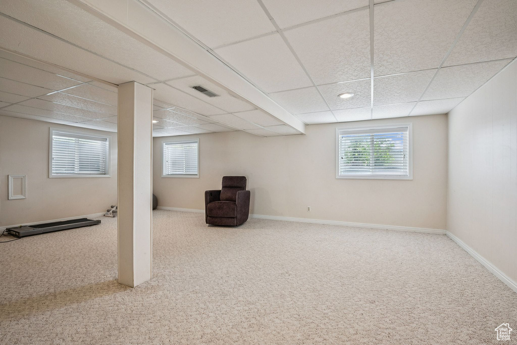 Basement featuring a paneled ceiling, carpet floors, and baseboards