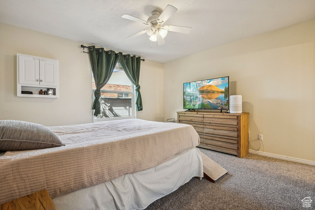 Bedroom featuring light colored carpet, ceiling fan, and baseboards