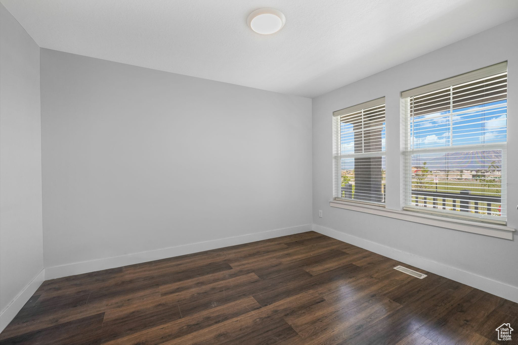 Spare room with dark wood-type flooring and baseboards