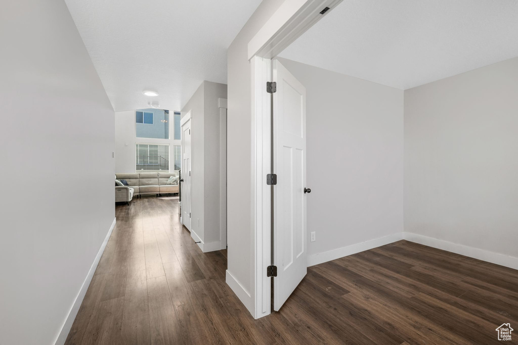 Corridor featuring dark wood-style flooring and baseboards