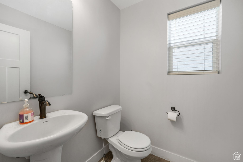 Half bath featuring a sink, baseboards, and toilet