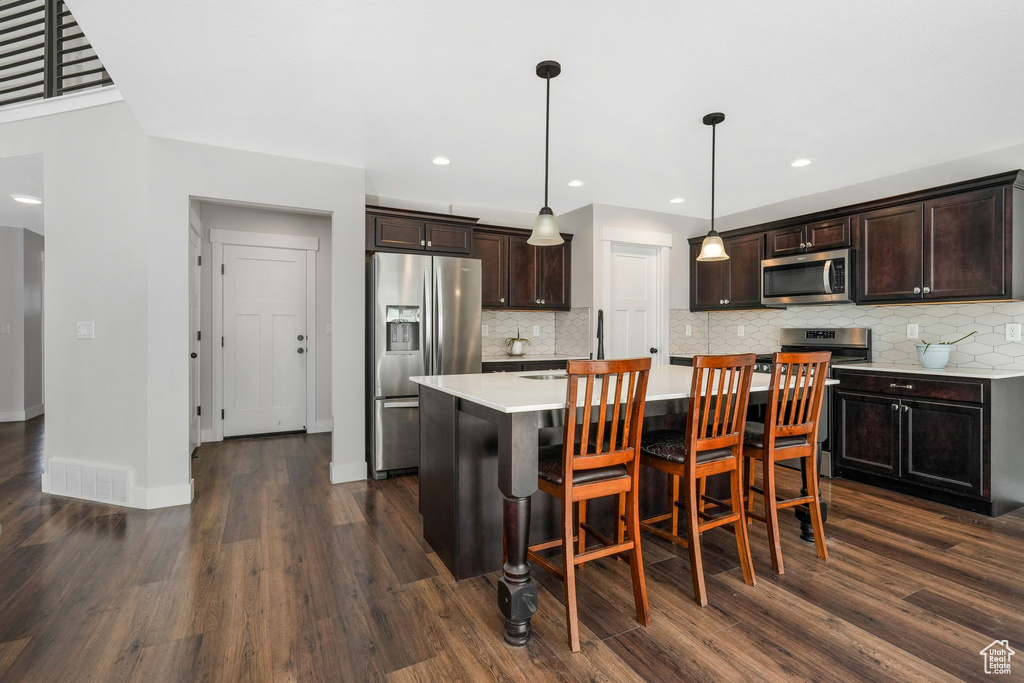 Kitchen featuring stainless steel appliances, light countertops, dark wood finished floors, tasteful backsplash, and recessed lighting