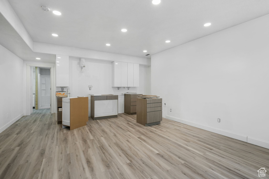 Kitchen with modern cabinets, white cabinetry, recessed lighting, light wood-style flooring, and baseboards