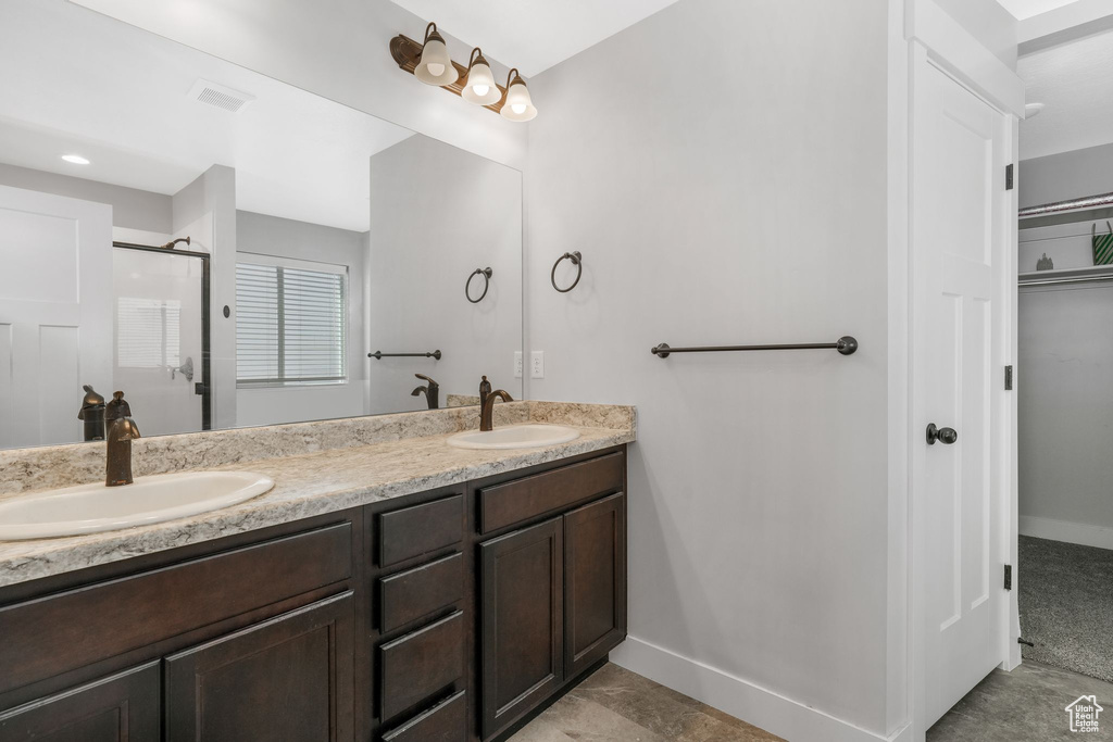 Full bathroom featuring double vanity, baseboards, and an enclosed shower