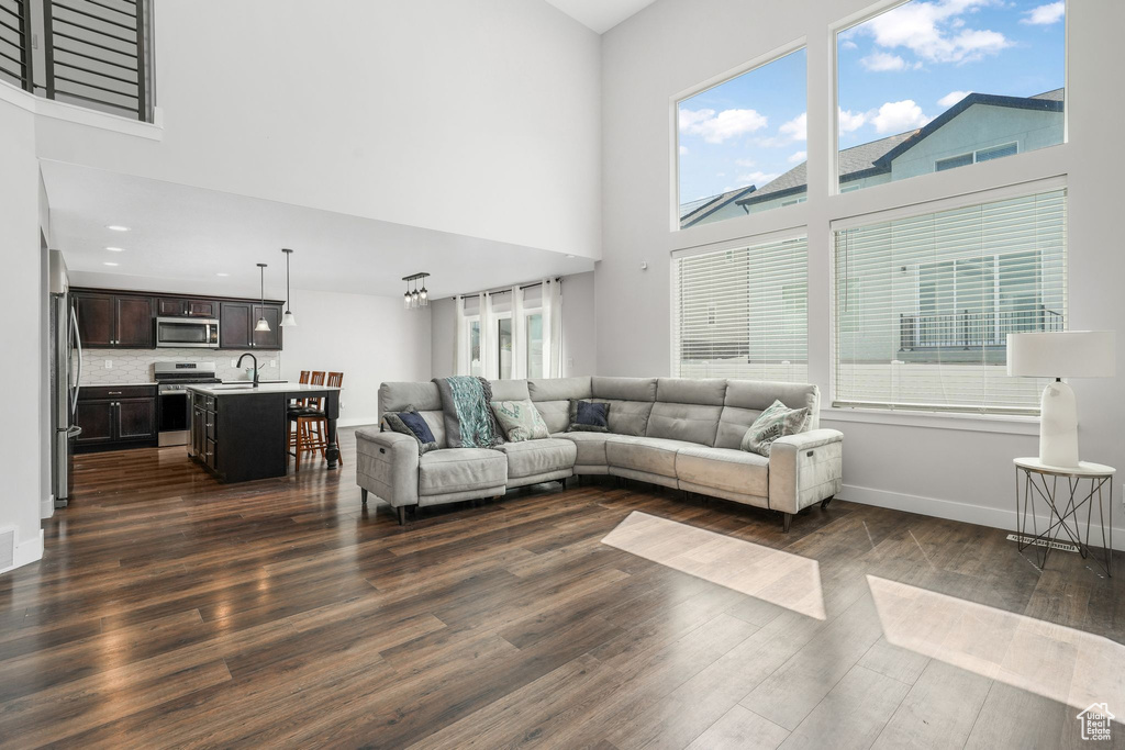 Living room featuring a high ceiling, dark wood finished floors, and baseboards