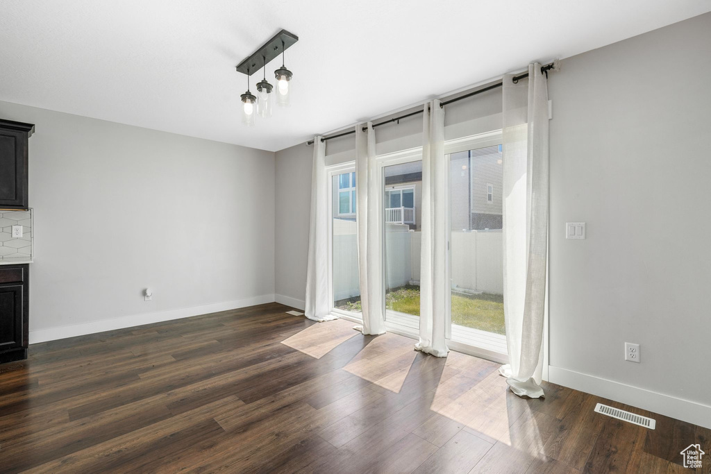 Unfurnished dining area with dark wood finished floors, baseboards, and a fireplace