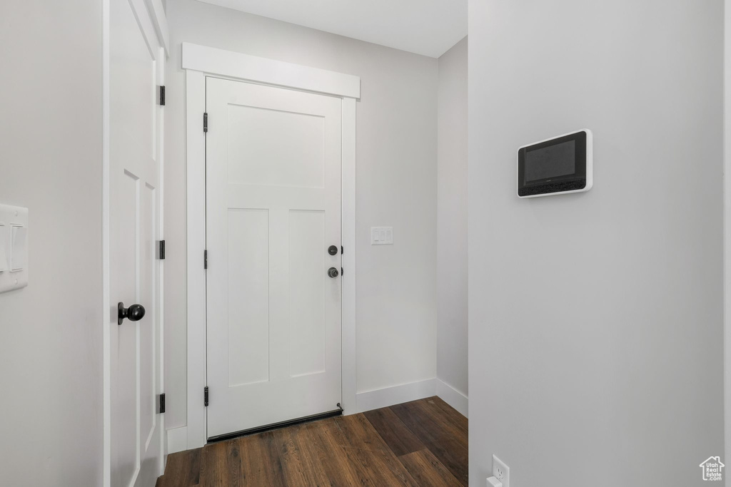 Doorway to outside with dark wood-style flooring and baseboards