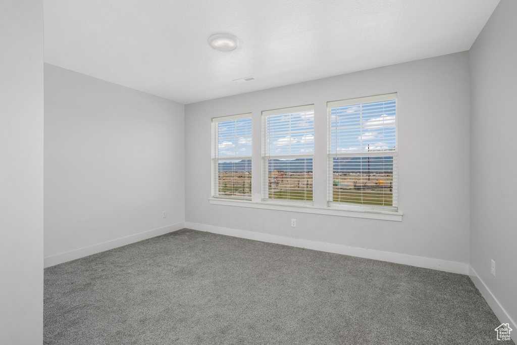 Spare room featuring carpet and baseboards