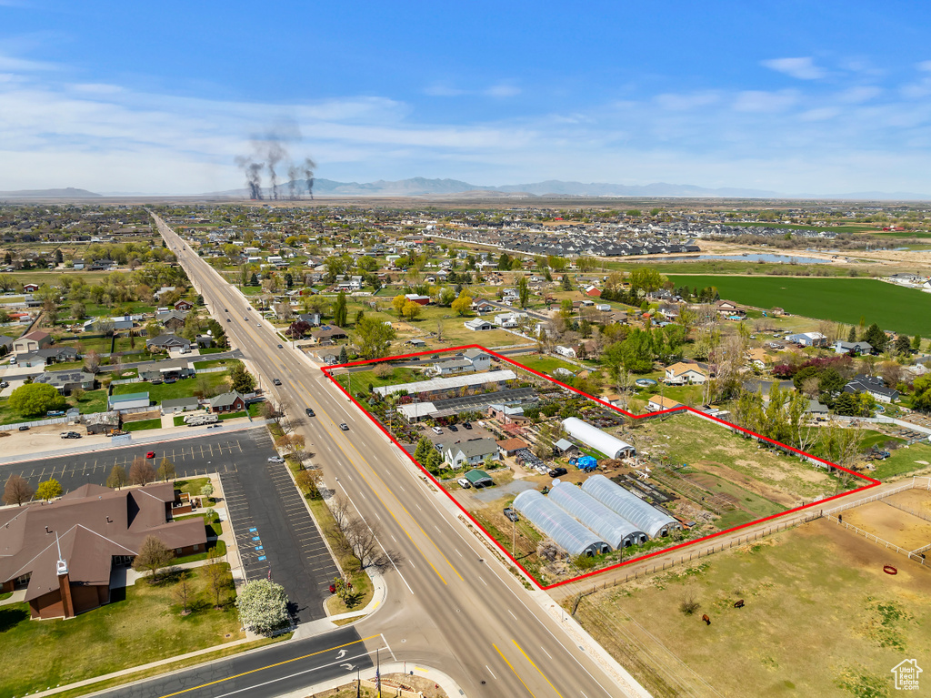 Aerial perspective of suburban area featuring property boundaries highlighted, a main thoroughfare, and a water and mountain view