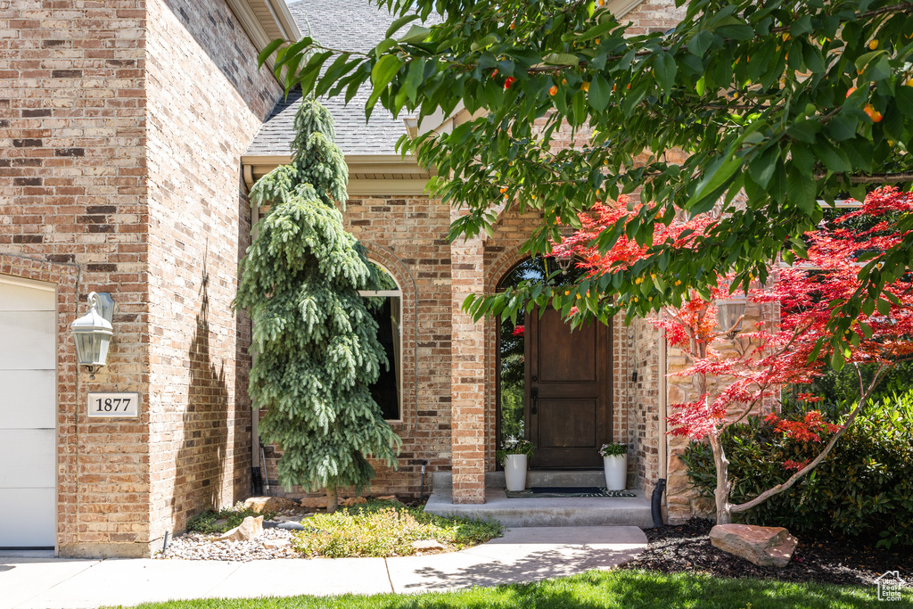 Property entrance with roof with shingles and brick siding