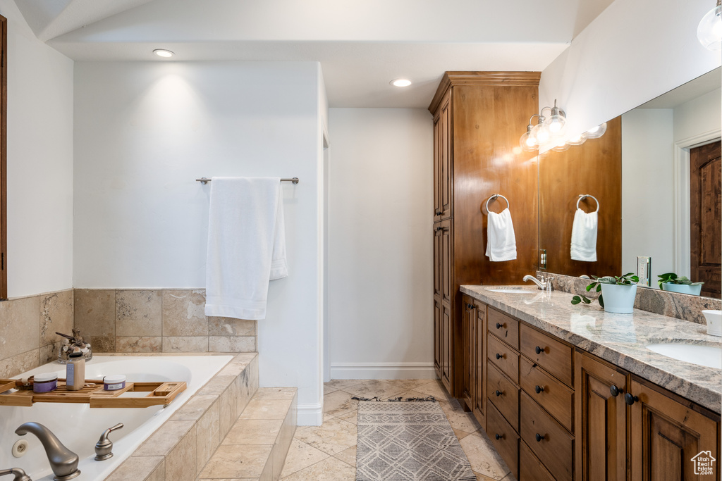 Bathroom featuring double vanity, a bath, and recessed lighting