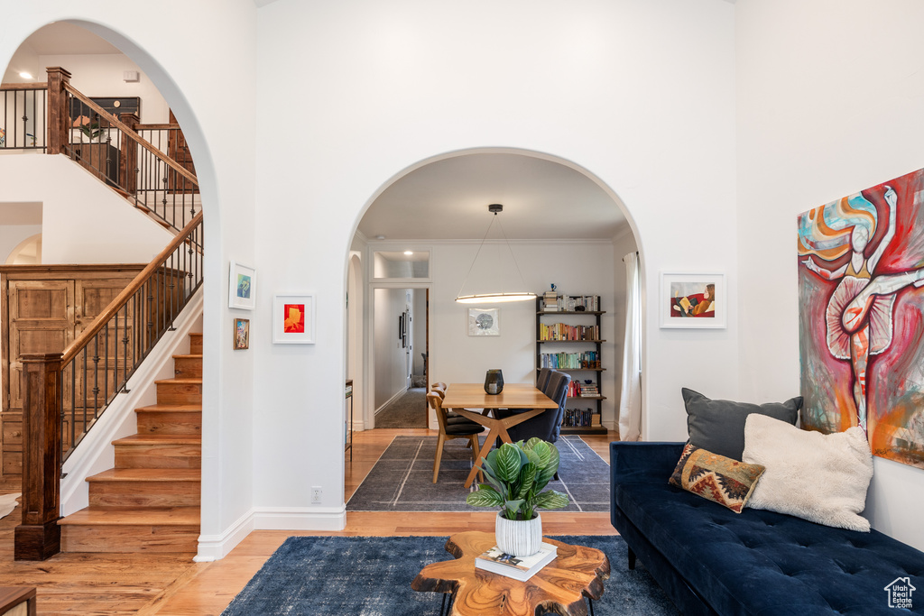 Living area featuring a towering ceiling, light wood-type flooring, stairway, arched walkways, and baseboards
