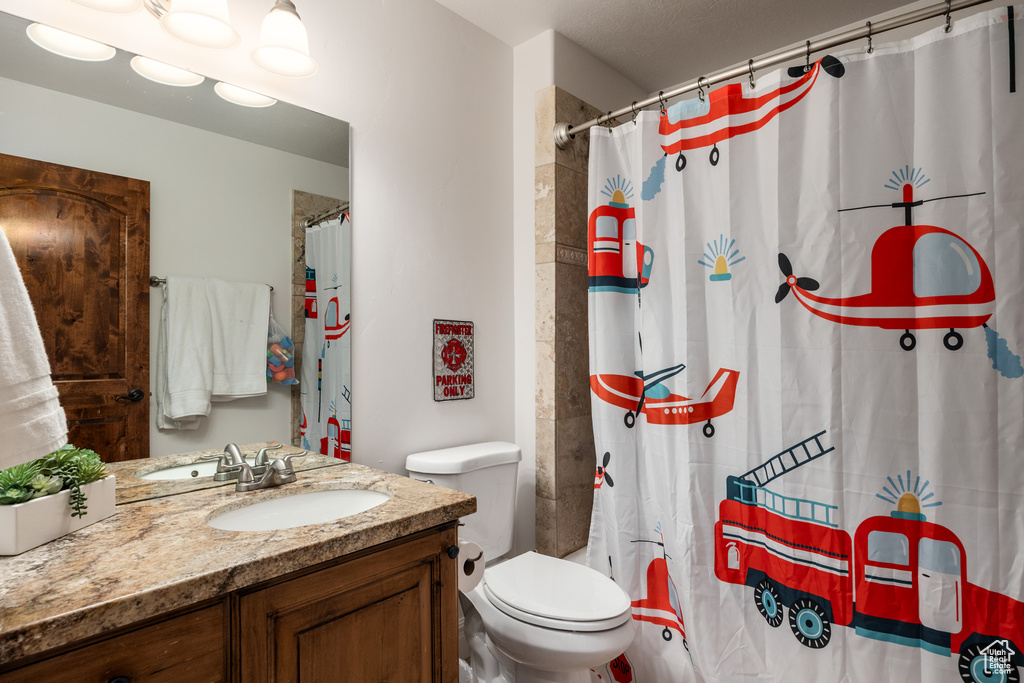 Bathroom featuring vanity, toilet, and a shower with shower curtain