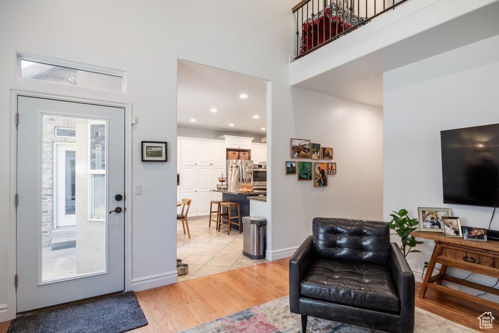 Foyer featuring light wood-style flooring, a high ceiling, baseboards, and recessed lighting
