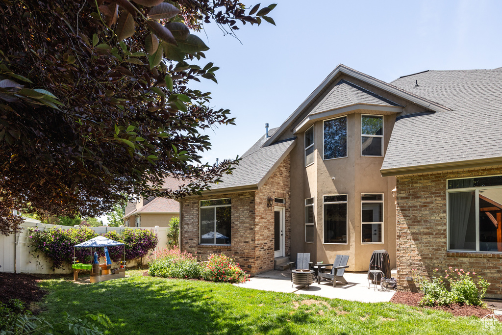 Back of house with brick siding, a patio, and a shingled roof