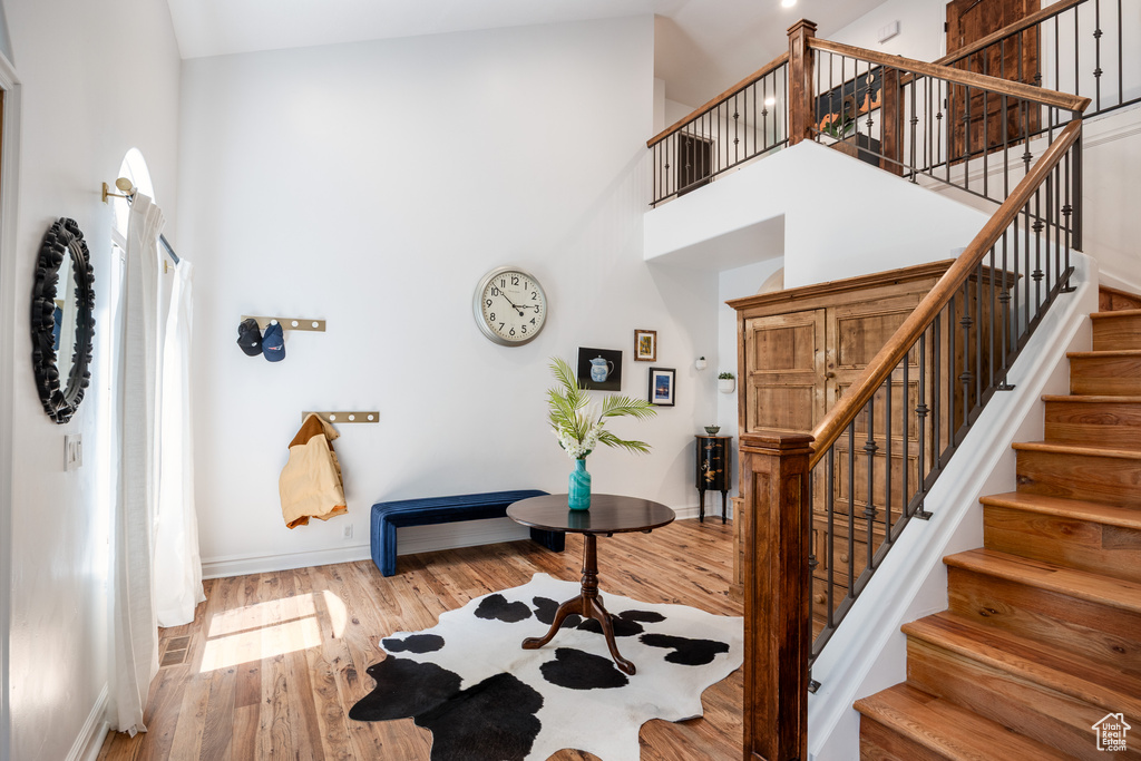 Entryway with high vaulted ceiling, stairway, wood finished floors, and baseboards