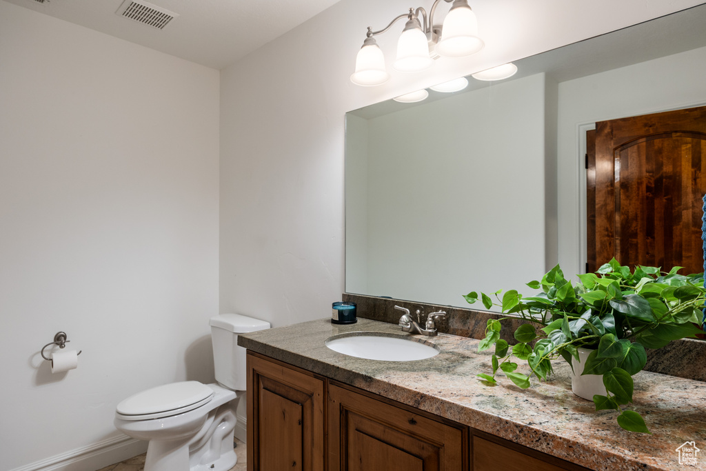 Bathroom featuring vanity, toilet, and baseboards