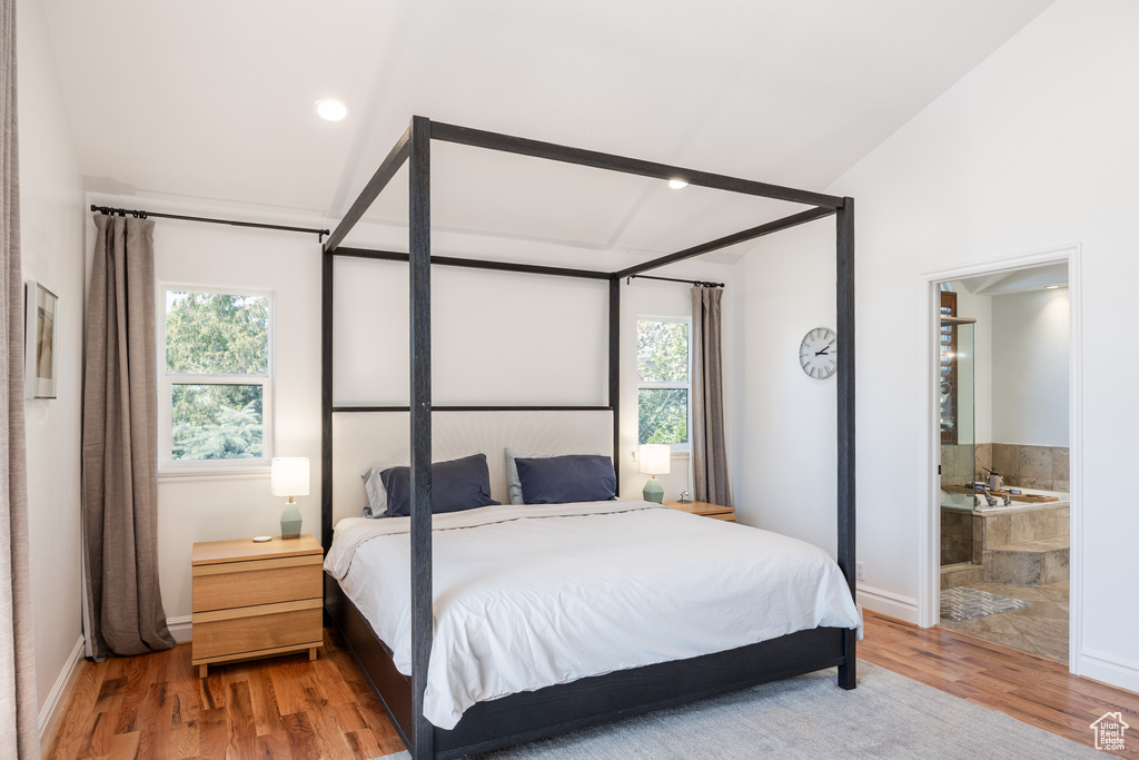 Bedroom featuring multiple windows, wood finished floors, lofted ceiling, baseboards, and ensuite bath