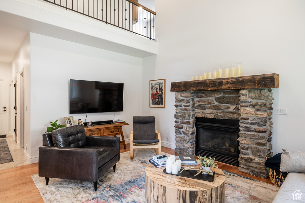 Living room with wood finished floors, a fireplace, a high ceiling, and baseboards