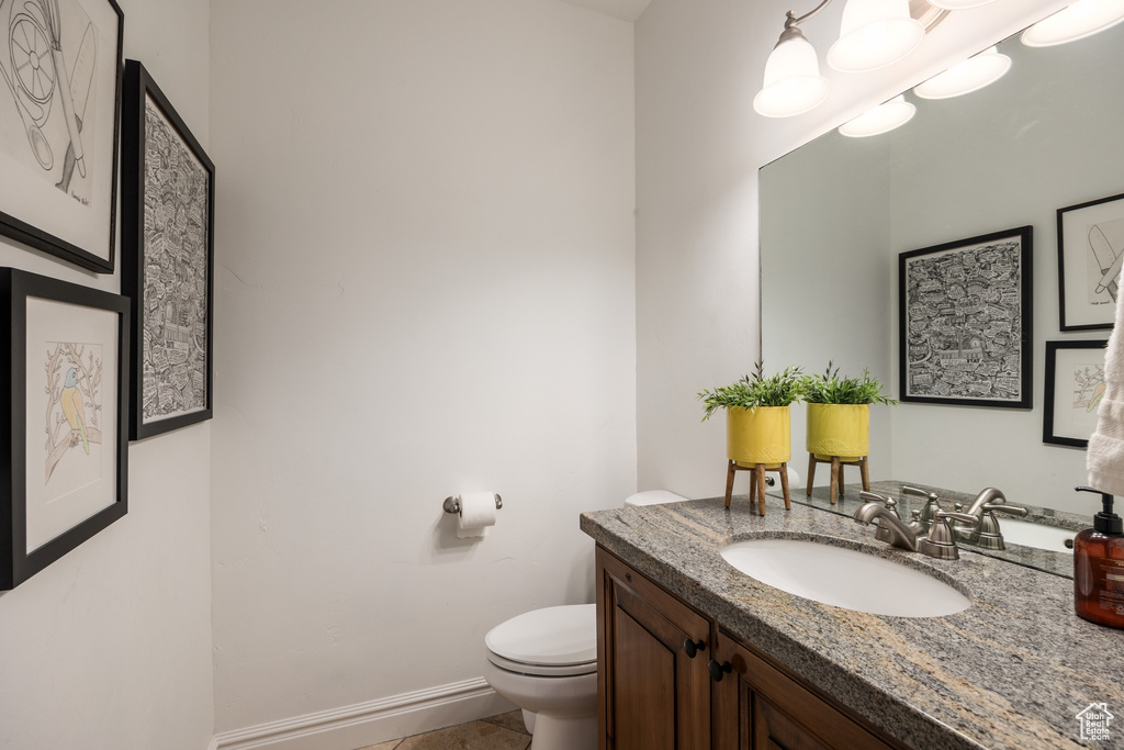 Bathroom featuring toilet, vanity, baseboards, and tile patterned flooring