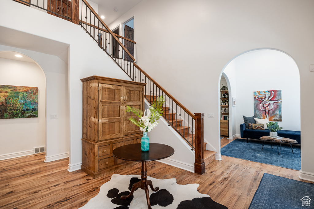 Foyer entrance featuring arched walkways, a high ceiling, wood finished floors, stairway, and baseboards