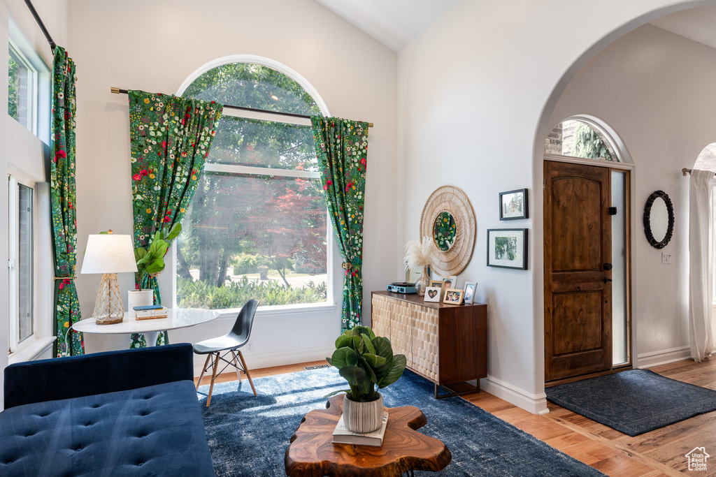 Foyer with arched walkways, wood finished floors, lofted ceiling, and baseboards