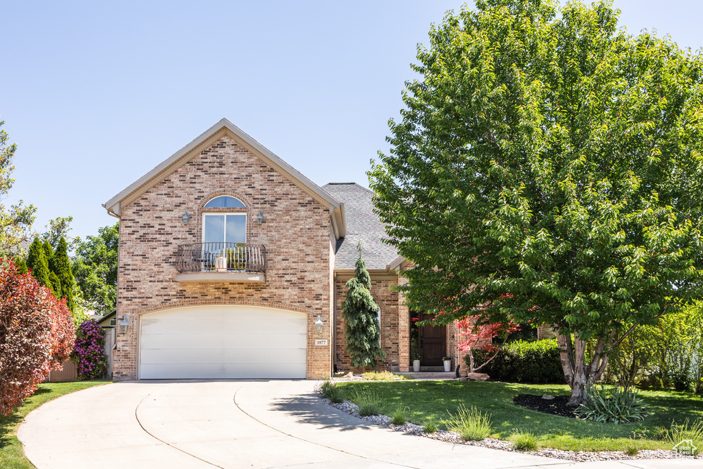 View of front facade with brick siding, driveway, a garage, and a front lawn