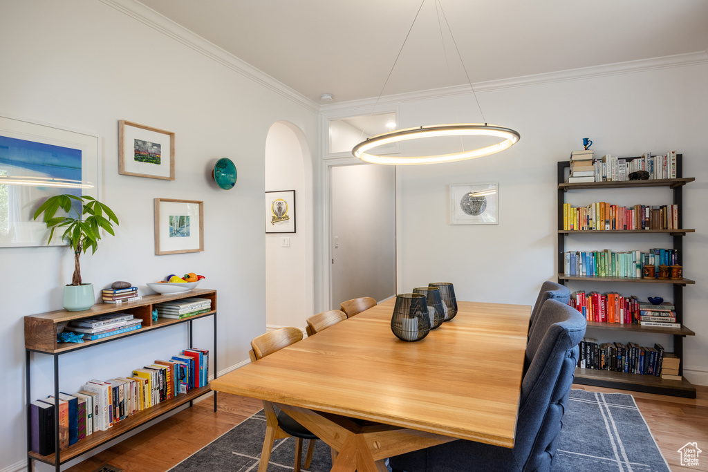 Dining space with crown molding, arched walkways, wood finished floors, and baseboards