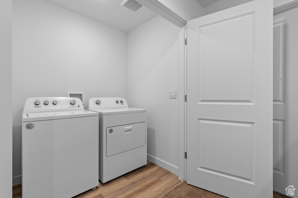 Washroom with washer and dryer, light wood-style flooring, and baseboards