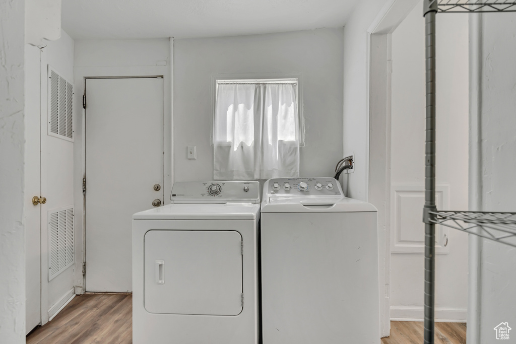 Laundry area with separate washer and dryer and light wood-style floors