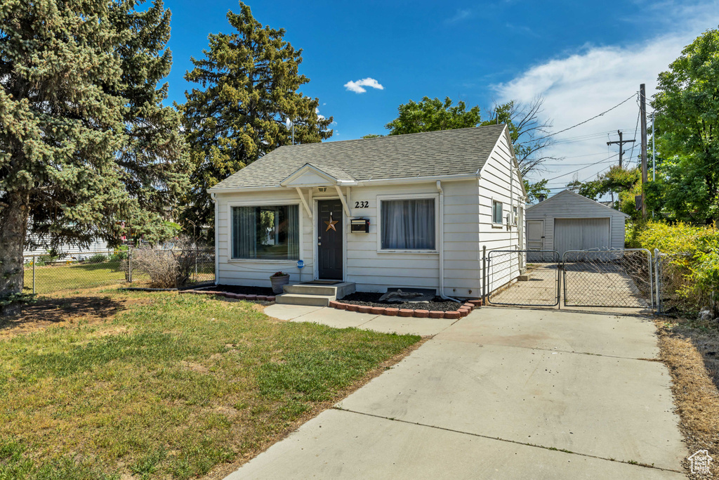 Bungalow-style house featuring a gate, a garage, a shingled roof, an outdoor structure, and driveway