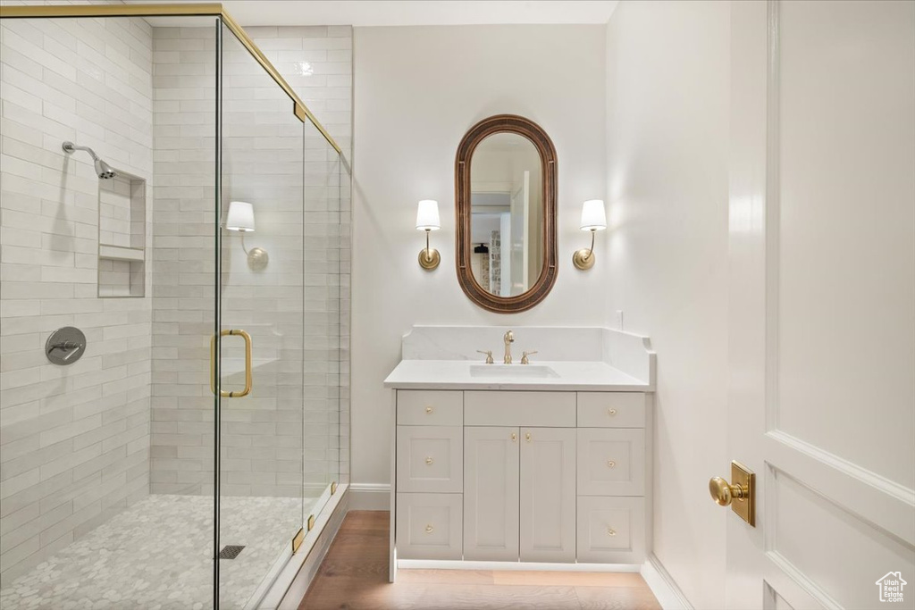 Bathroom with a stall shower, vanity, baseboards, and wood finished floors