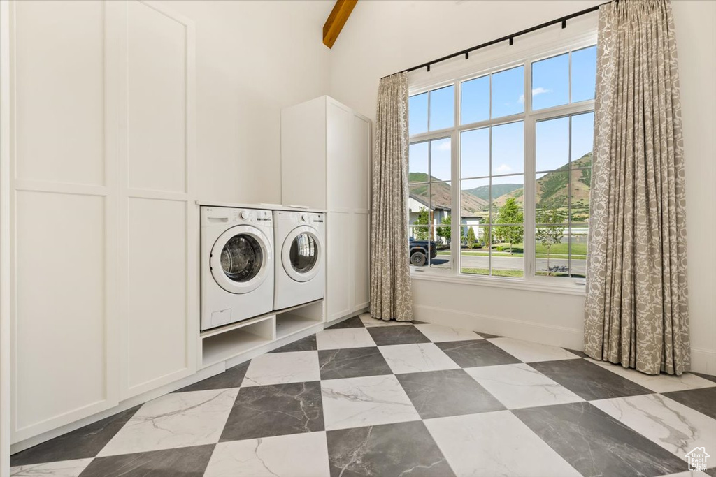 Laundry room with independent washer and dryer, baseboards, and a high ceiling