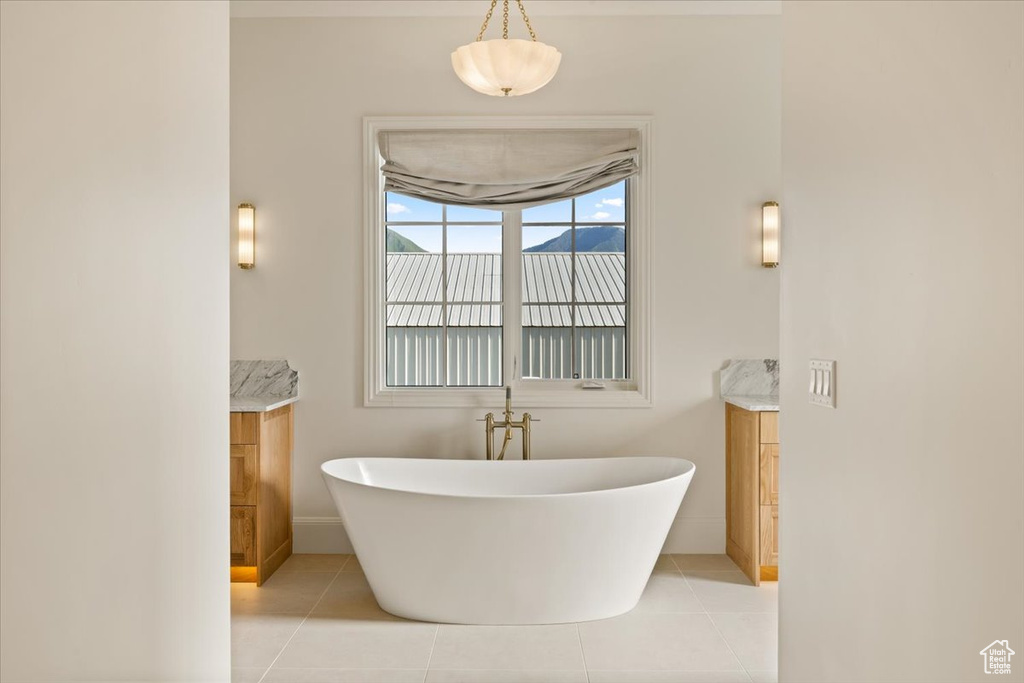 Full bathroom featuring vanity, a soaking tub, tile patterned flooring, and baseboards