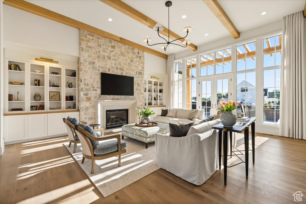 Living area featuring beam ceiling, a chandelier, a fireplace, wood finished floors, and recessed lighting