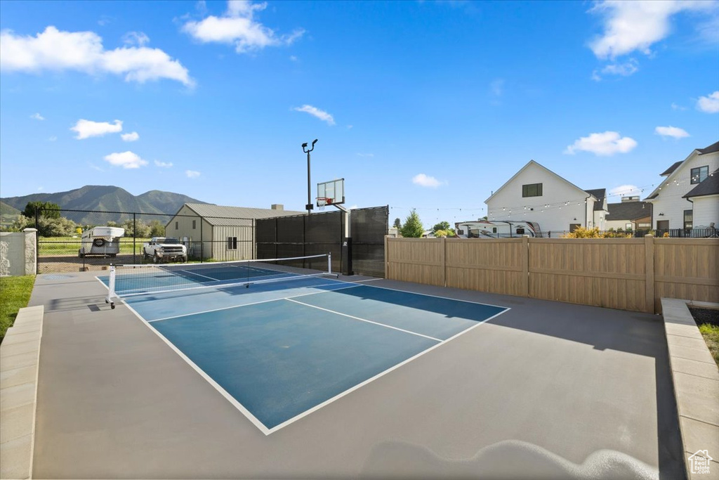 View of tennis court featuring a mountain view, basketball hoop, and a residential view