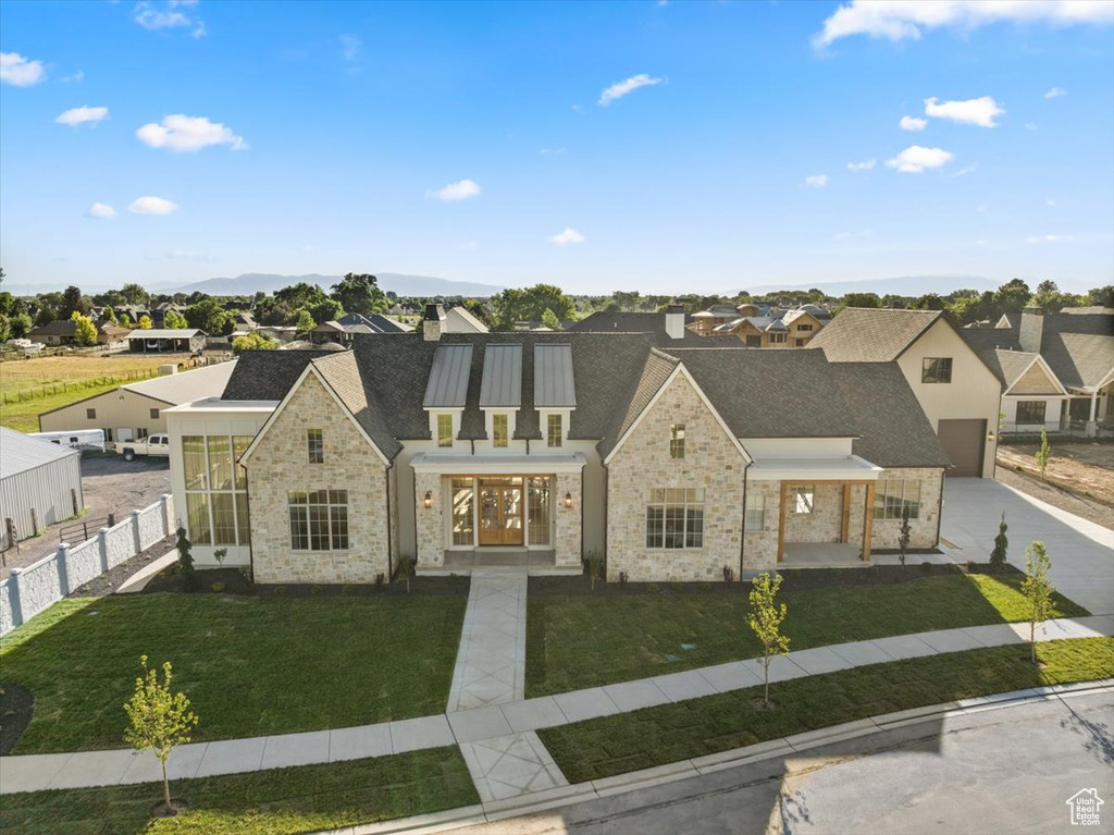 View of front of home featuring a residential view, stone siding, driveway, a garage, and a shingled roof