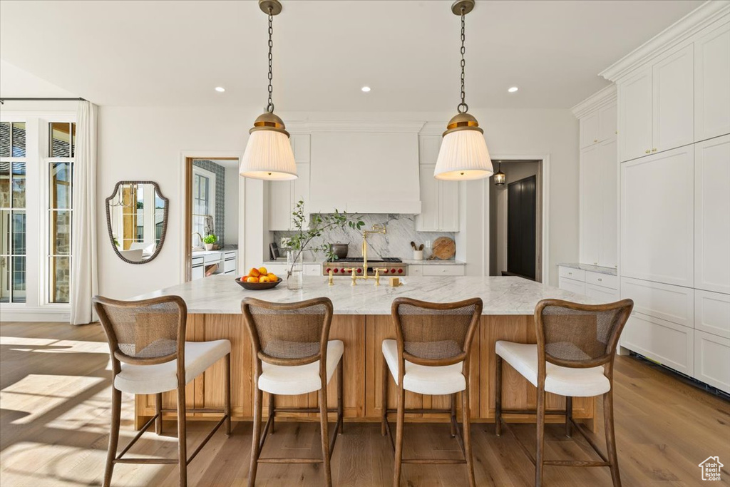 Kitchen featuring decorative backsplash, wood finished floors, white cabinetry, pendant lighting, and recessed lighting
