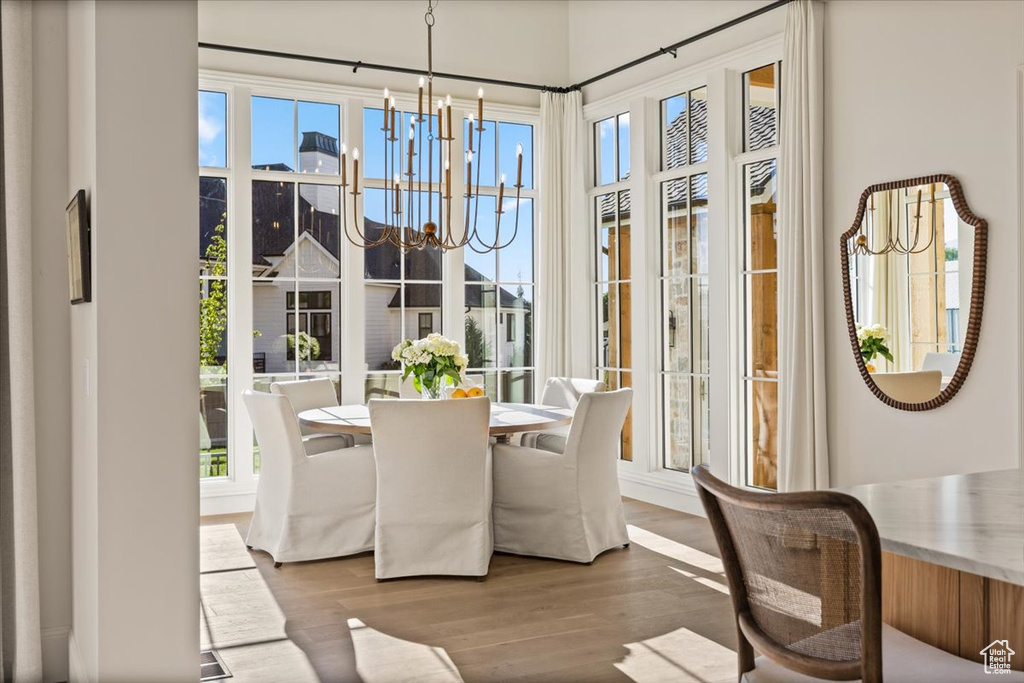 Dining space with a chandelier, wood finished floors, and healthy amount of natural light