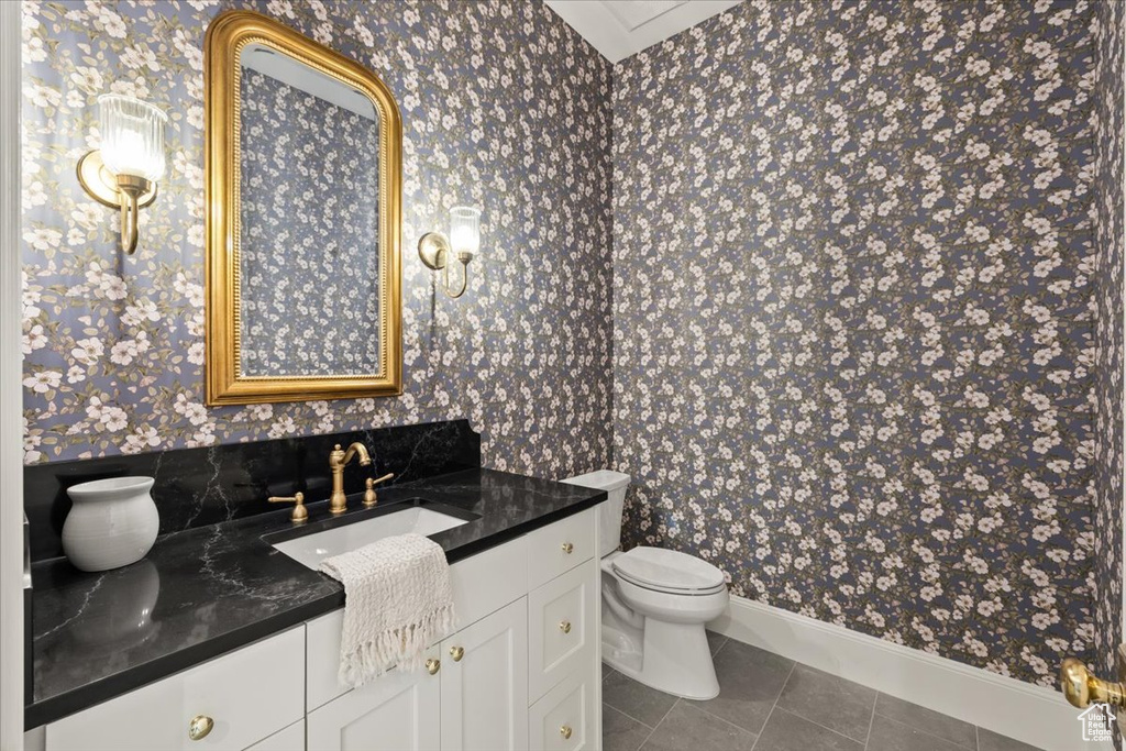 Bathroom featuring wallpapered walls, vanity, toilet, tile patterned floors, and baseboards