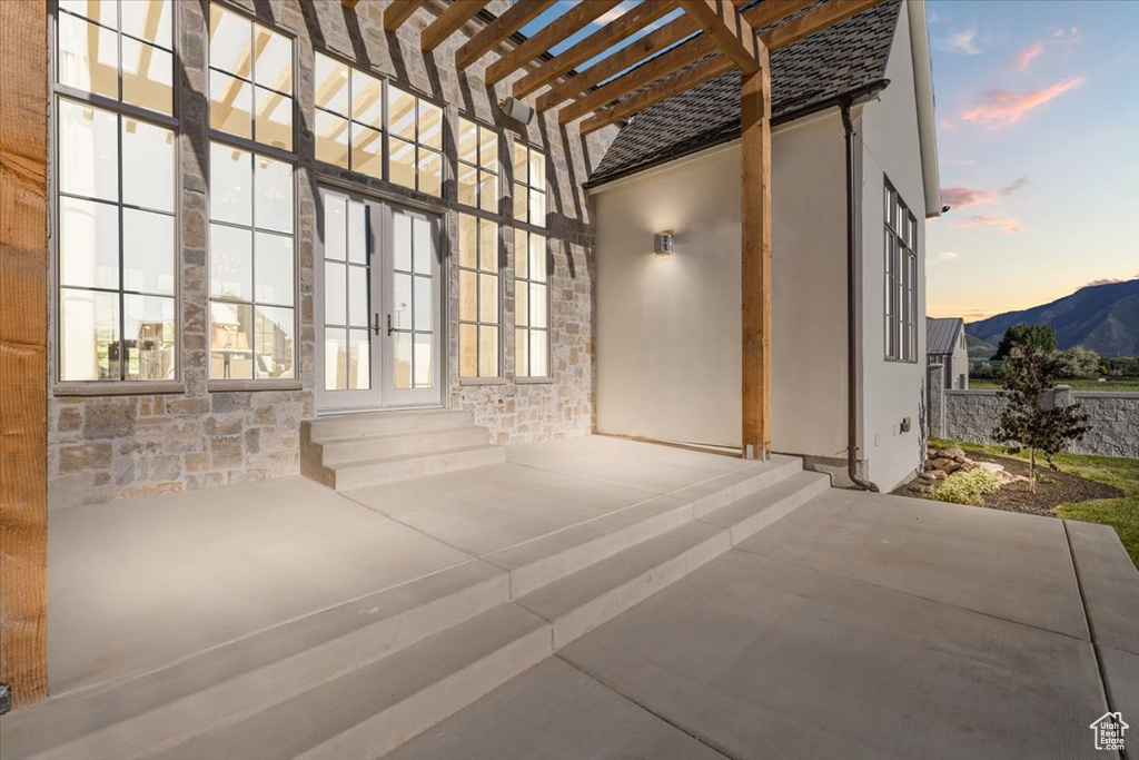 Patio terrace at dusk with french doors, a pergola, a patio area, and a mountain view
