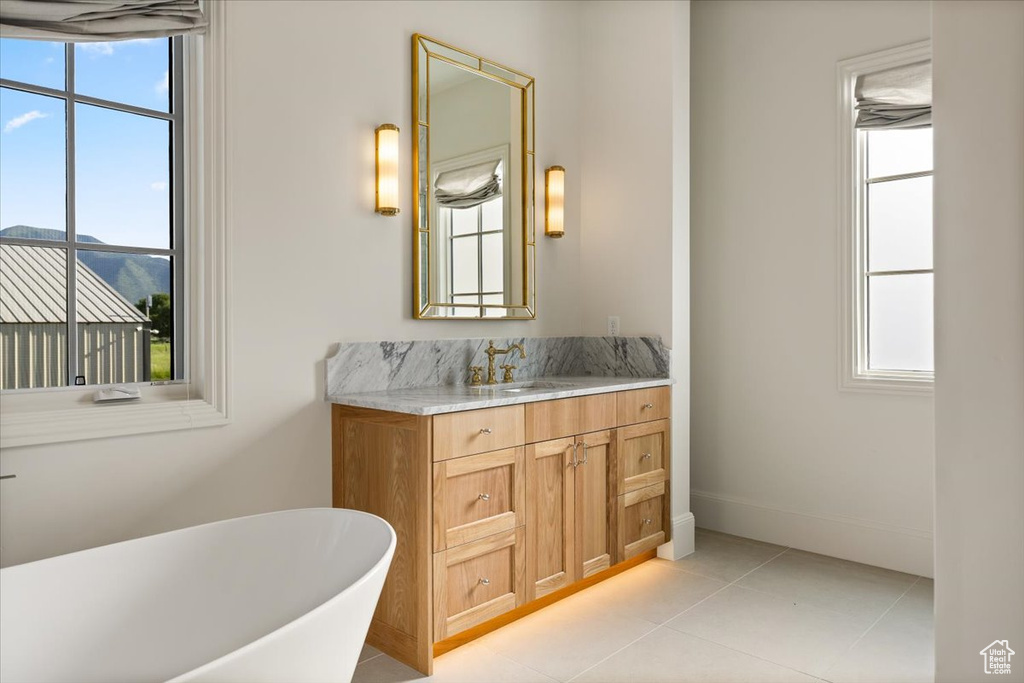 Bathroom featuring a freestanding bath, vanity, plenty of natural light, and tile patterned flooring