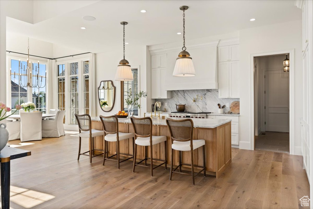 Kitchen with backsplash, light wood-style flooring, recessed lighting, white cabinetry, and a kitchen island with sink