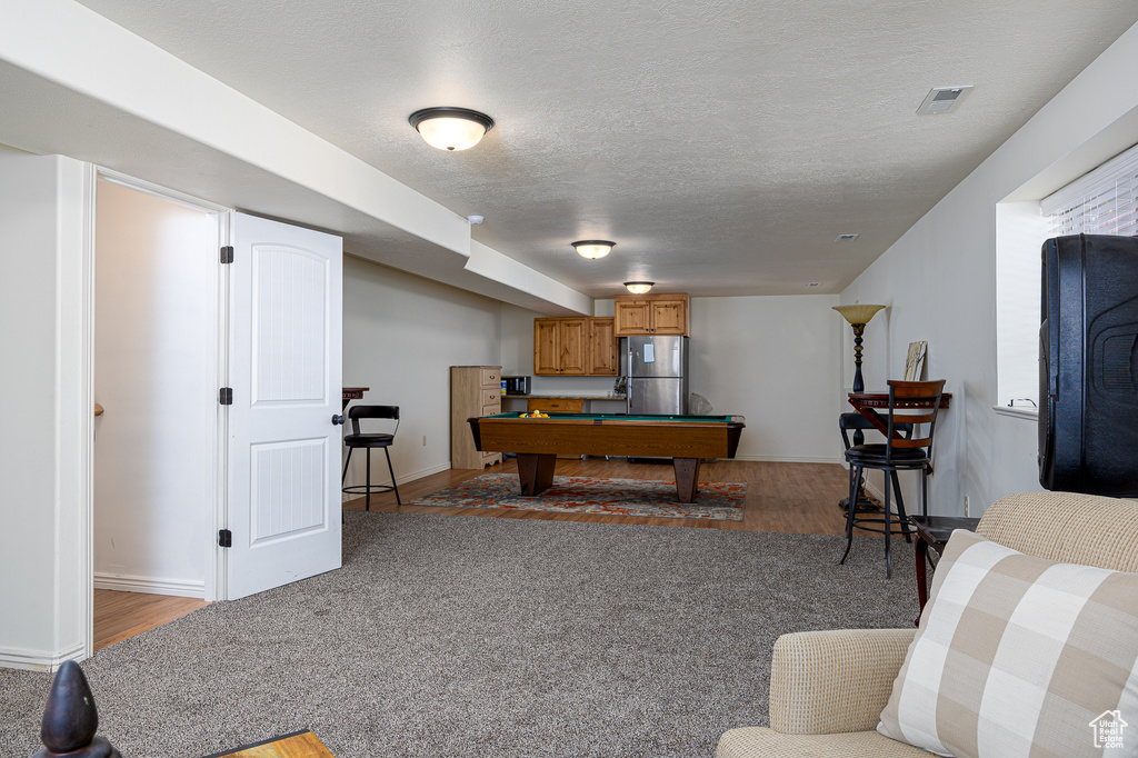 Game room featuring billiards, light wood finished floors, baseboards, and a textured ceiling