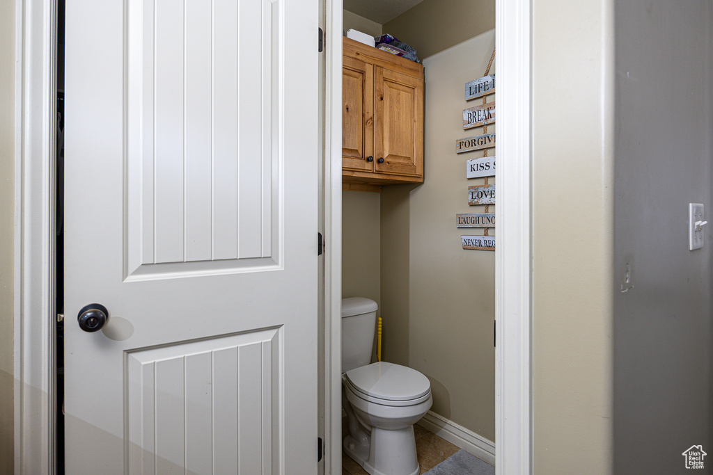 Bathroom featuring toilet, baseboards, and tile patterned flooring