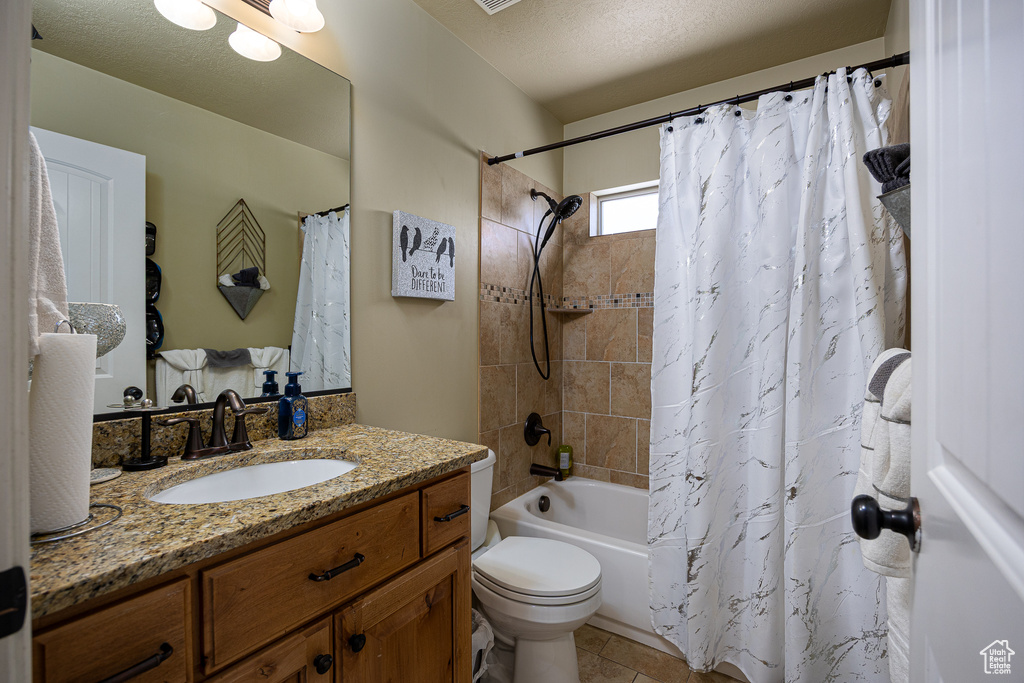 Bathroom featuring vanity, shower / tub combo, toilet, and tile patterned floors