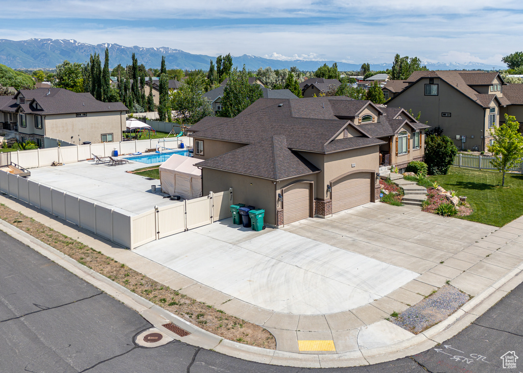 View of front facade featuring a gate, a shingled roof, a residential view, stucco siding, and concrete driveway