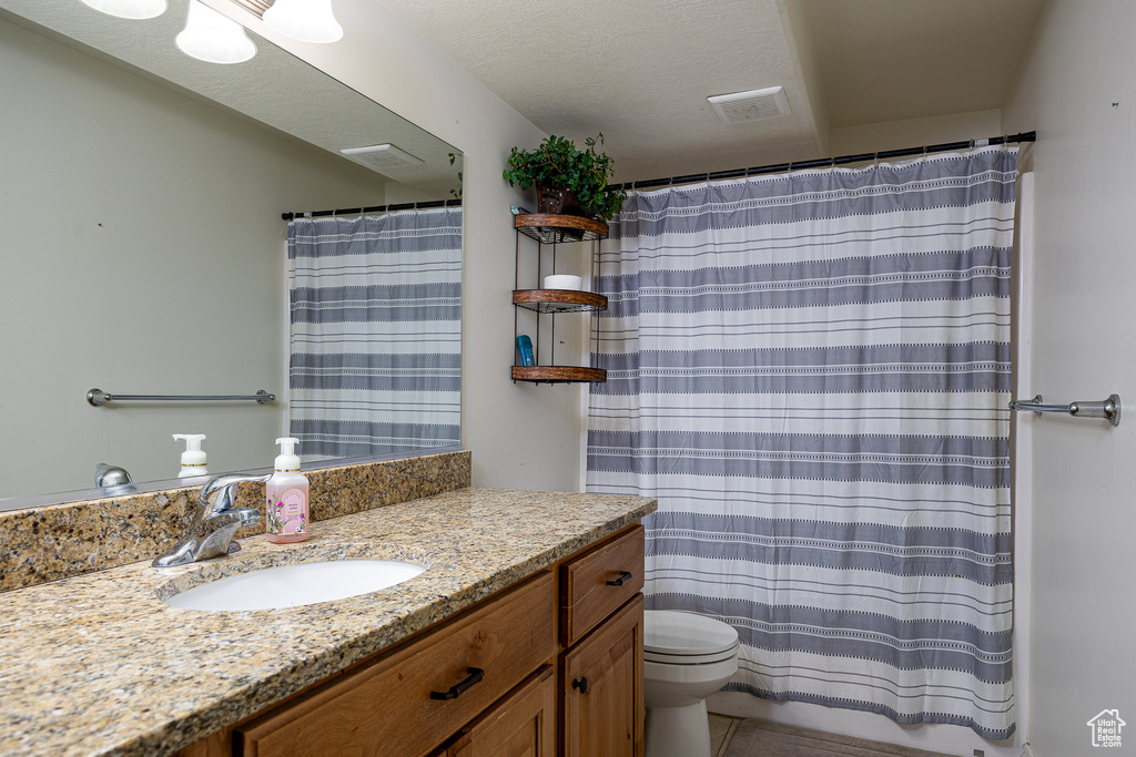Bathroom featuring vanity, toilet, curtained shower, and tile patterned flooring
