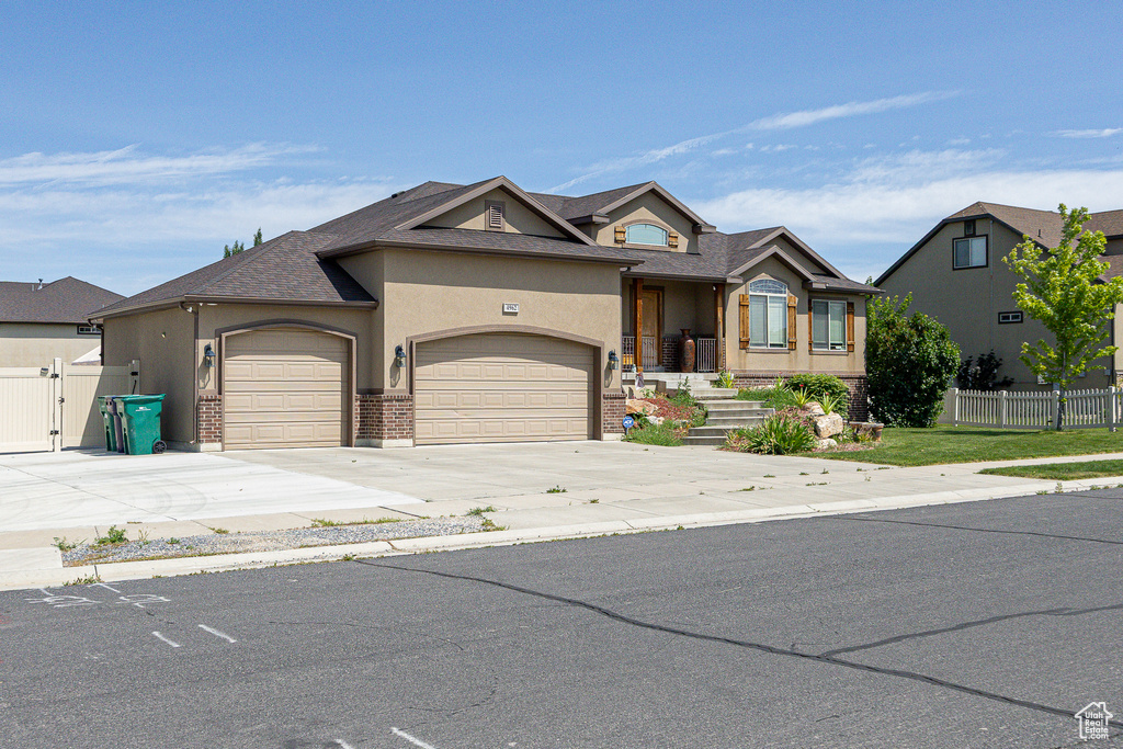 View of front of home featuring a garage, stucco siding, driveway, roof with shingles, and a gate